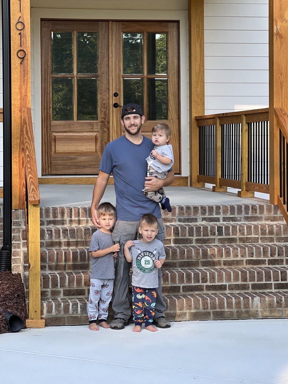 Zach and his 2 children standing outside of a home